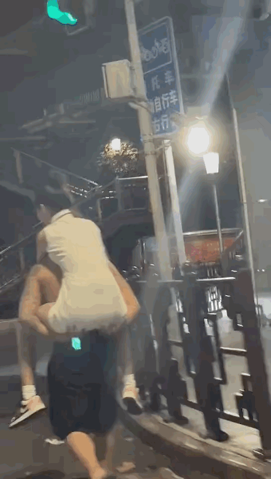 开车的朋友路边偶然发现一位年轻男士背着女孩行走，向他俩打了一声招呼，男女青年冲着