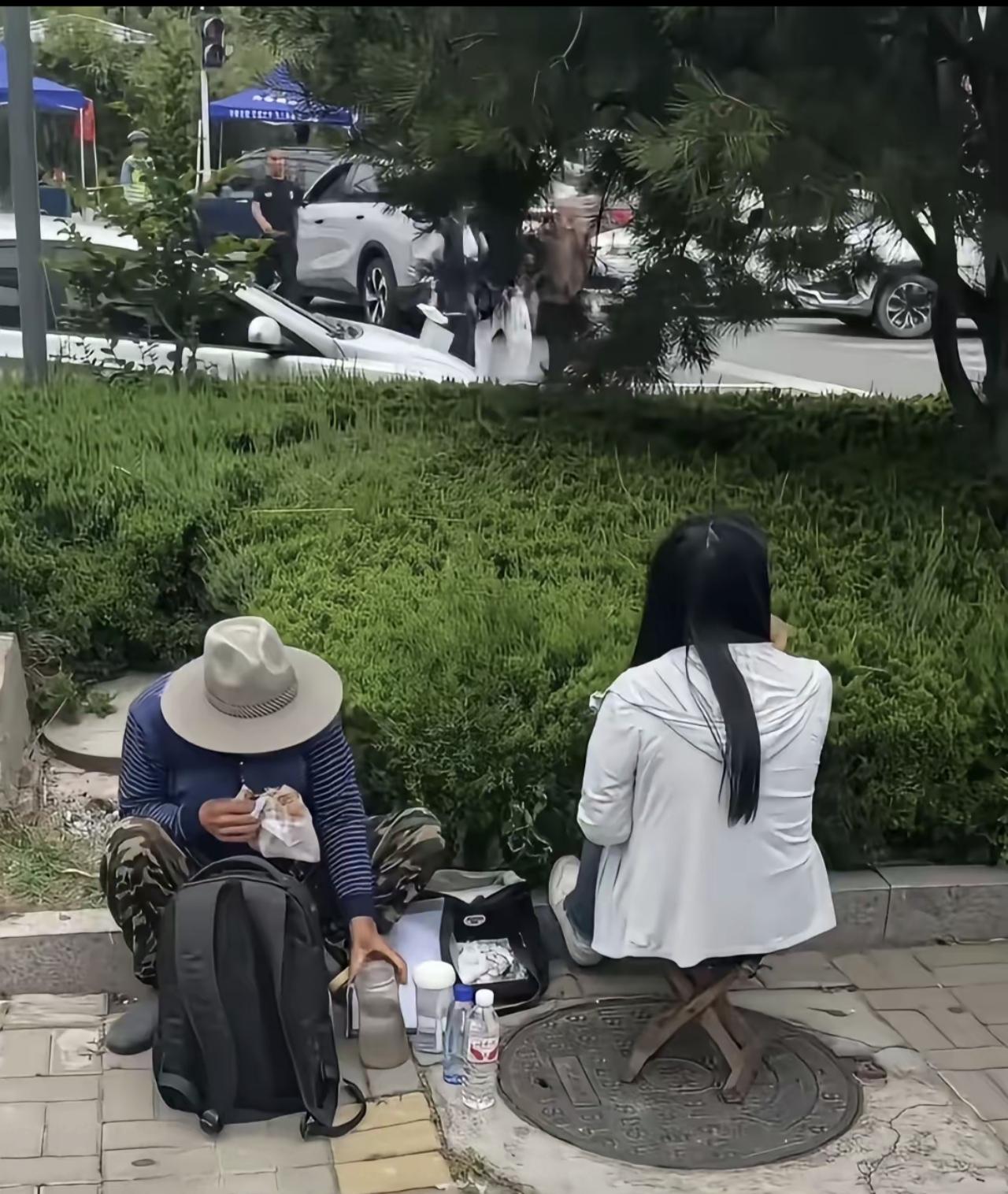 这是在高考马路也拍到的一幕，一位大爷大概60多岁，底头吃着手里的煎饼，旁边坐着一