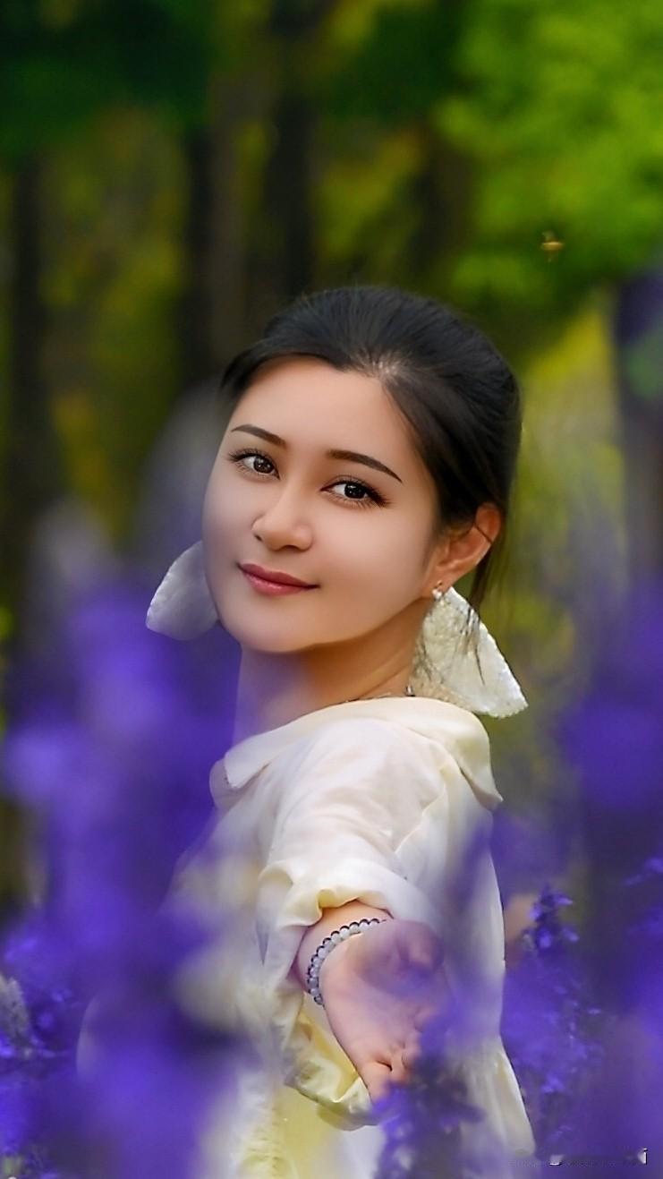 紫雾缭绕群山，春光晕染清欢。
   白衣女子伫立花间，回眸之际眼波盈盈流转，伸手