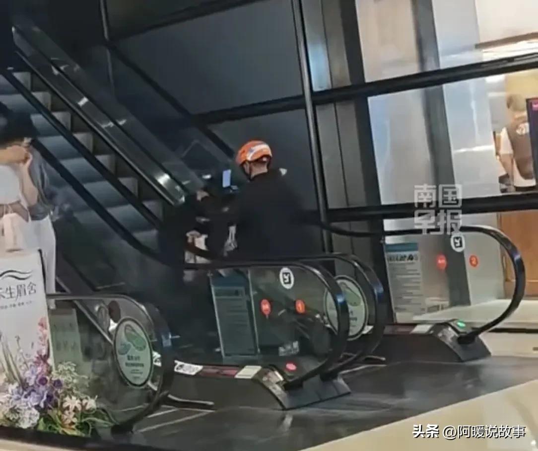 北京一商场里，外卖小哥骑电动车上了自动扶梯，一旁的路人看呆了。自动扶梯一节一节的