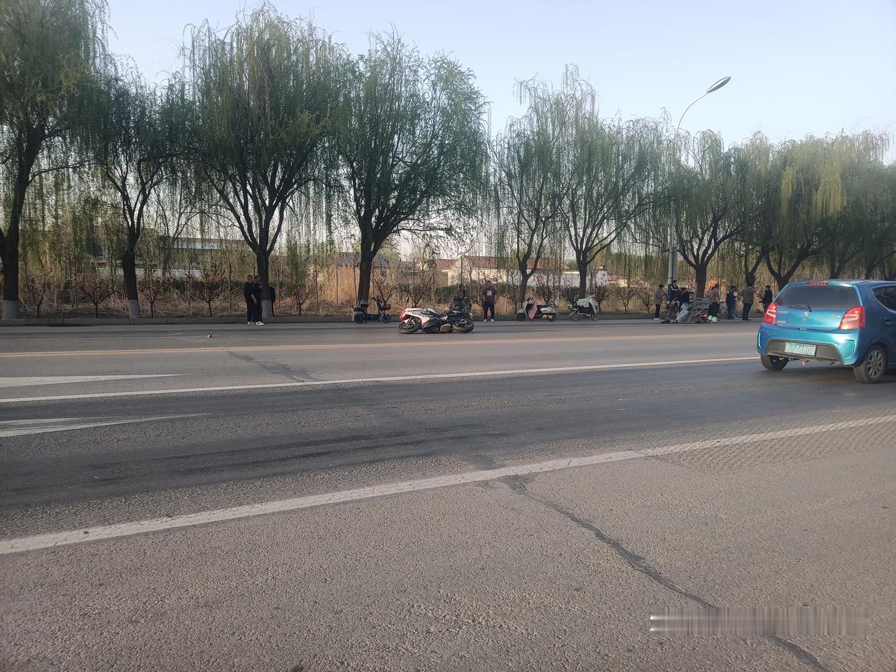 下班路上，一辆白色125摩托车倒在路上，旁边是一辆电车子，看样子是电车子逆行，摩