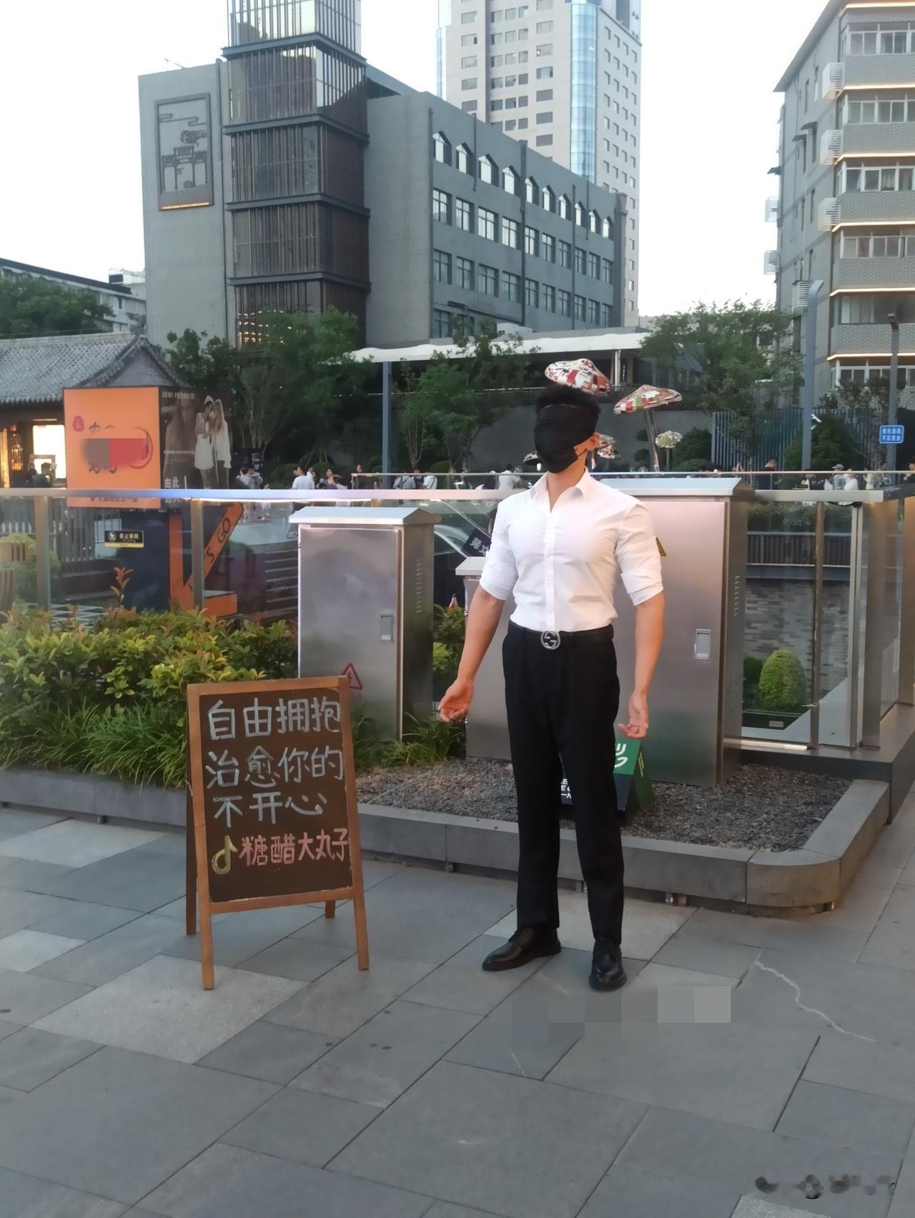 “免费拥抱”。徐州街头，一年轻男子戴着面罩，张开双臂，等待相拥。旁边牌子上写着“
