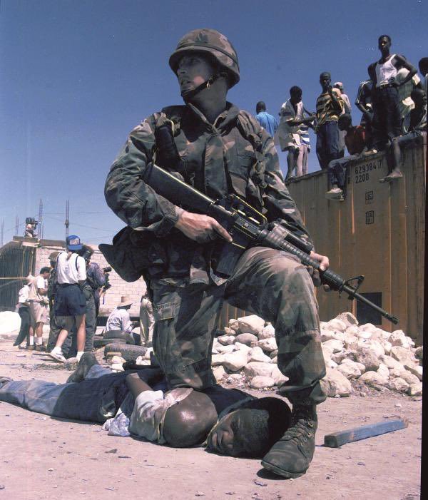 1994年，美国占领海地期间，一名全副武装的海军陆战队员压在一名海地人的背上。 