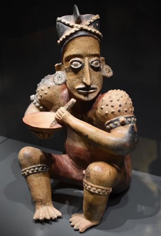 这是公元前300年墨西哥的陶俑，一名男子戴着耳饰研磨食物，表情生动，仿佛厌倦了日