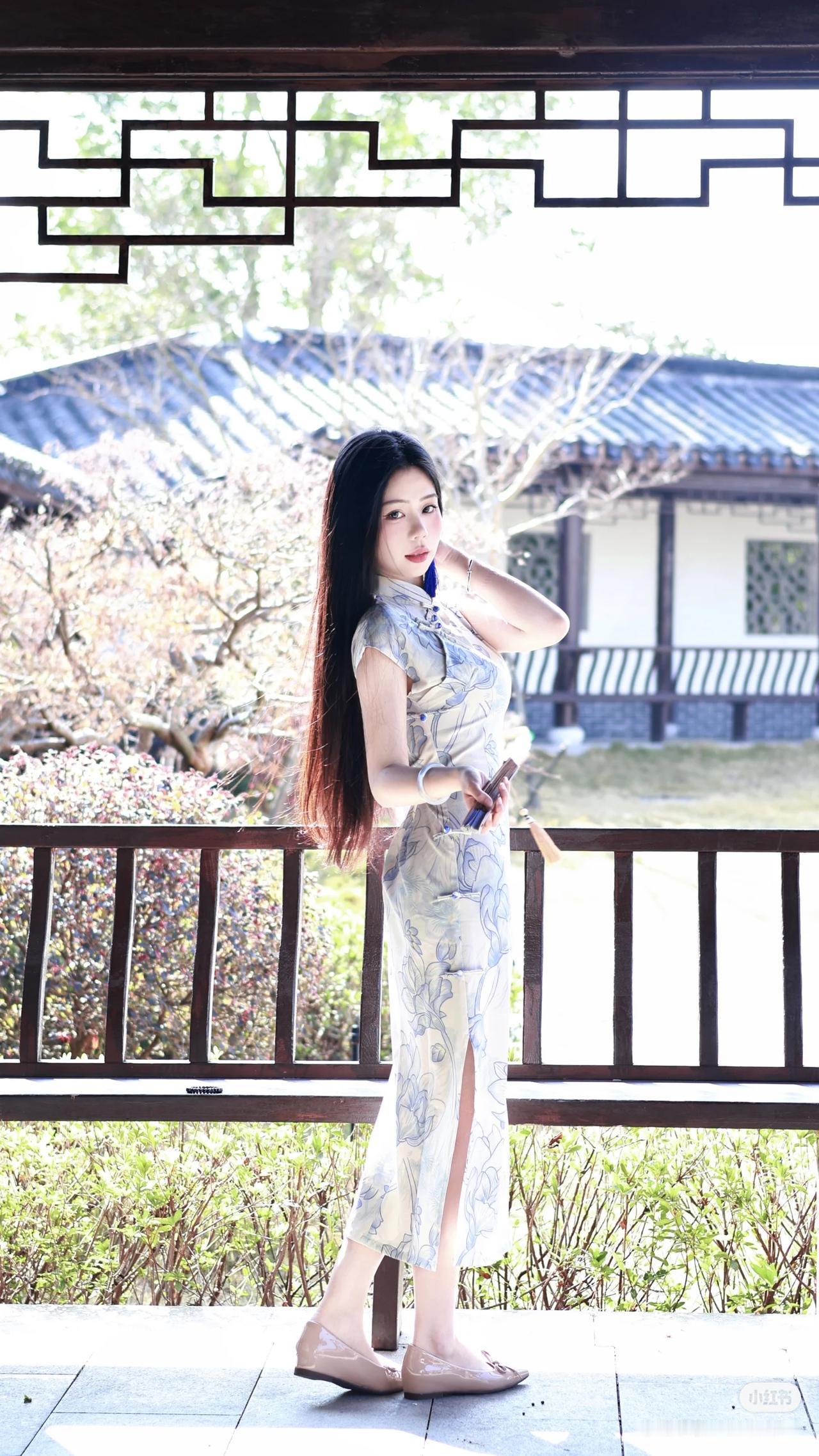 女子身穿浅底蓝花旗袍，搭配蓝色流苏耳饰与浅色高跟鞋，手持折扇，或倚栏、或坐 be