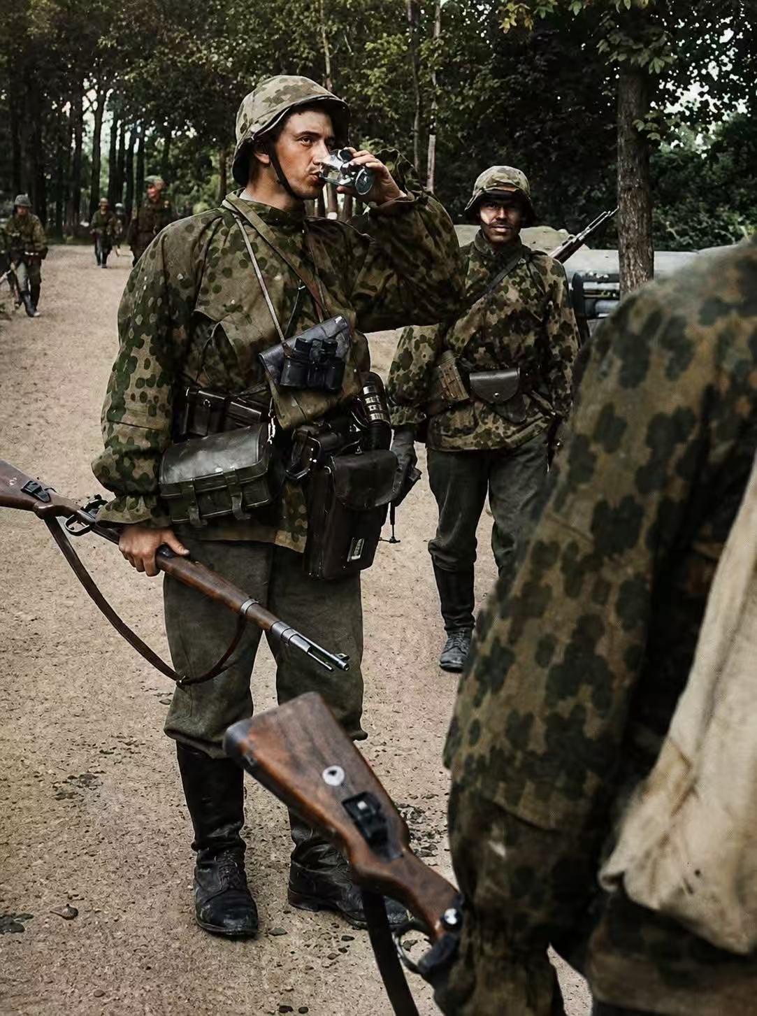 照片记录了二战东线战场，德国武装档卫军步兵在林间小道上休息的场景。
一名士兵正