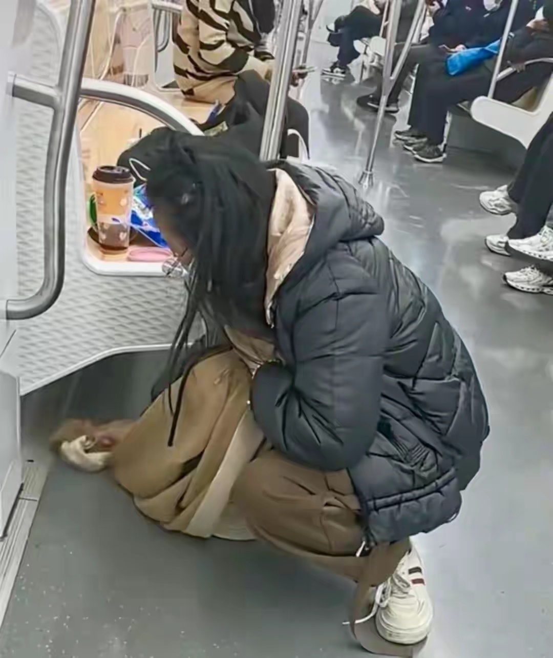 江苏苏州一位女乘客在地铁上不慎打翻奶茶后，用随身携带的围巾仔细擦拭弄脏的座椅和地