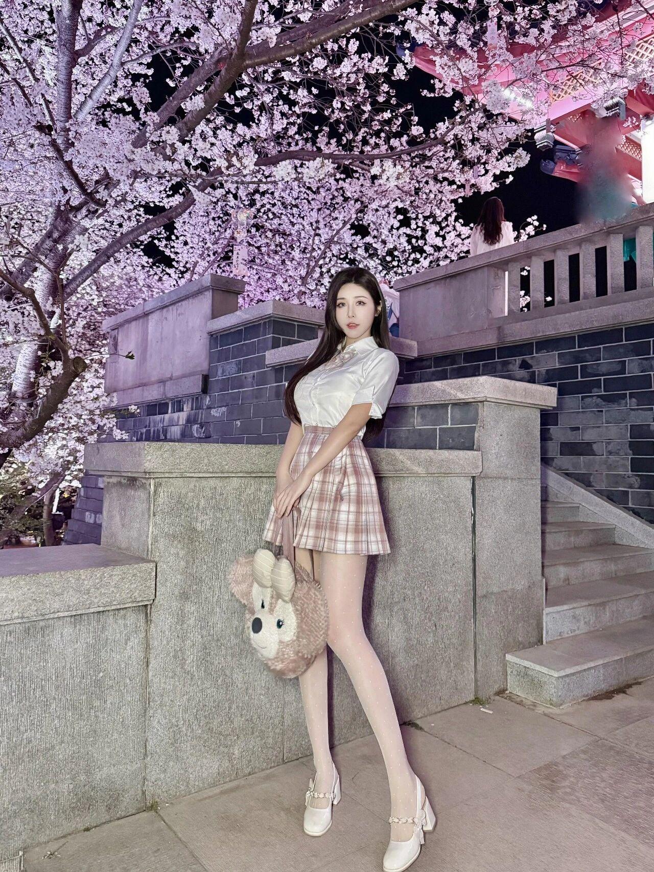 整体画面
夜色中的樱花林如梦似幻，满树繁花在灯光映照下呈现出梦幻的粉紫色调，营造