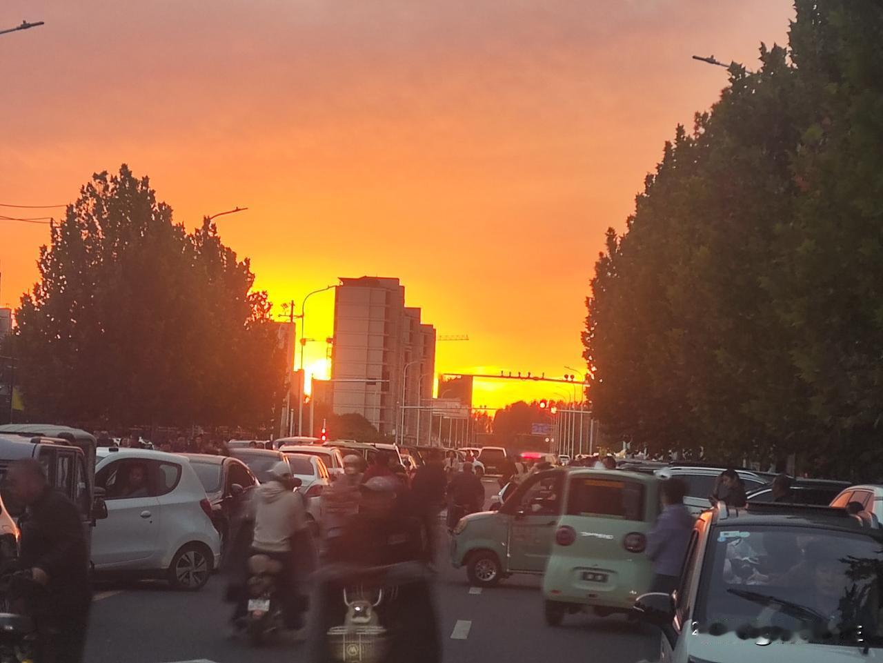 夕阳铺满天际，漫天橙红霞光，把城市街道染成温暖的画卷。车流涌动，行人往来，这是人