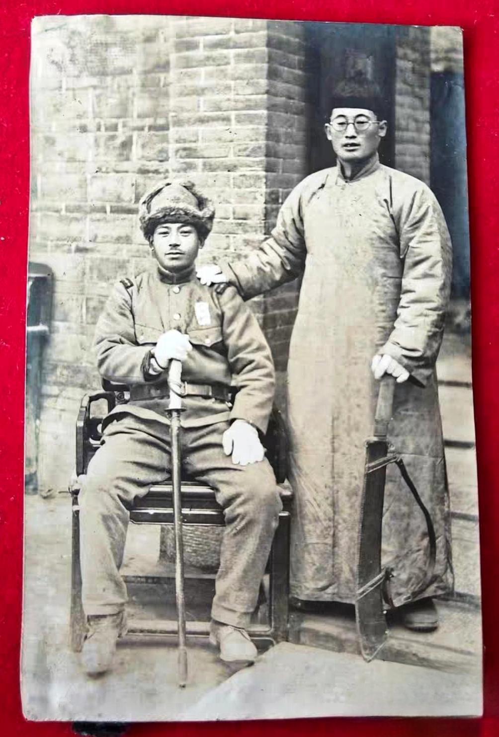这是一名日军和一位村民的合照。这名日军从军衔上看应该是一位军曹，只见他坐在红木八