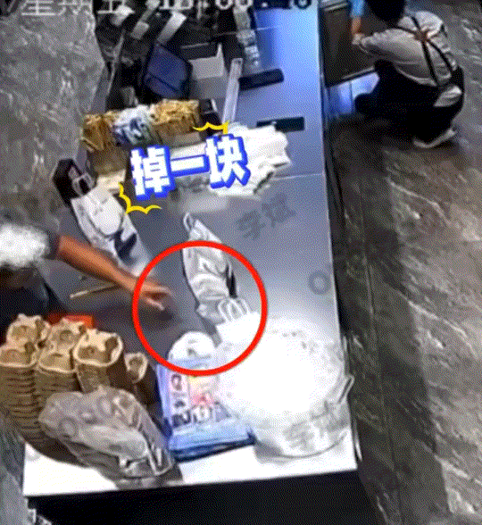 一饮品店内，工作人员将冰柜里的冰块铲进冰桶里待用，可铲的过程中一块冰就掉到了桌子