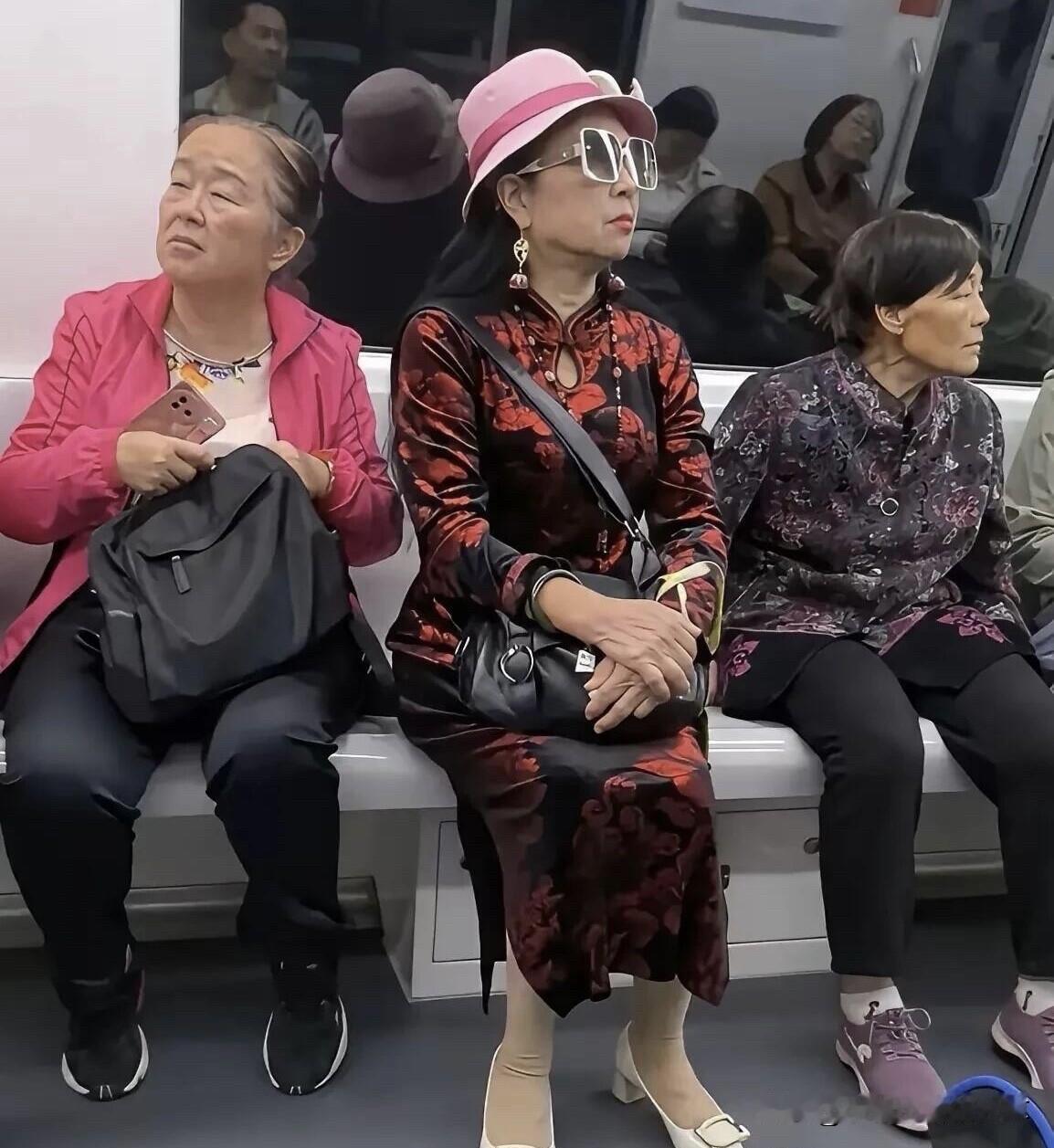 中间的这一位大妈真是会打扮，戴着洋气的帽子，一副墨镜，身穿深红色的旗袍，身材还依