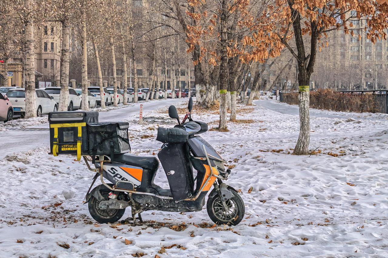 雪隅孤车
 
寒冬余雪，立春已至。观塘公园旁林隅雪地，一台外卖电动车静静停驻十余