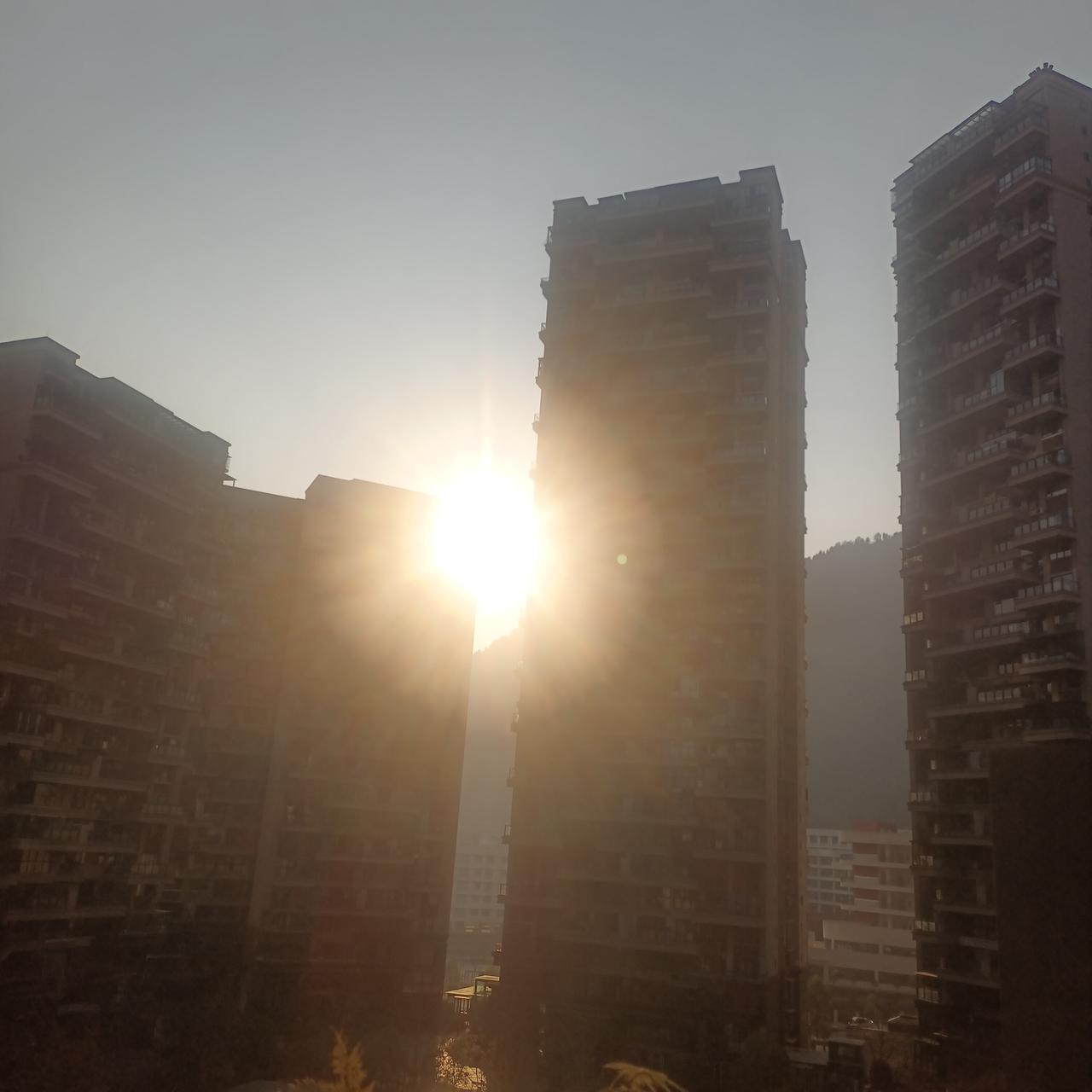 城市晨曦，高楼林立，阳光穿透云层，照亮希望。