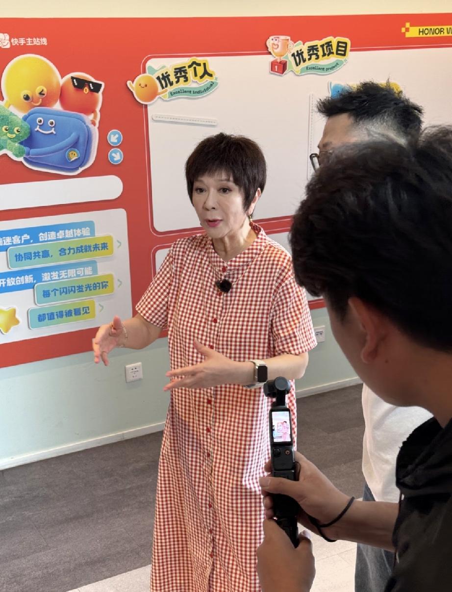 6月10日，蔡明在北京访问快手总部，戴樱桃耳环、黑色腕表，远看还行，近看就是一个
