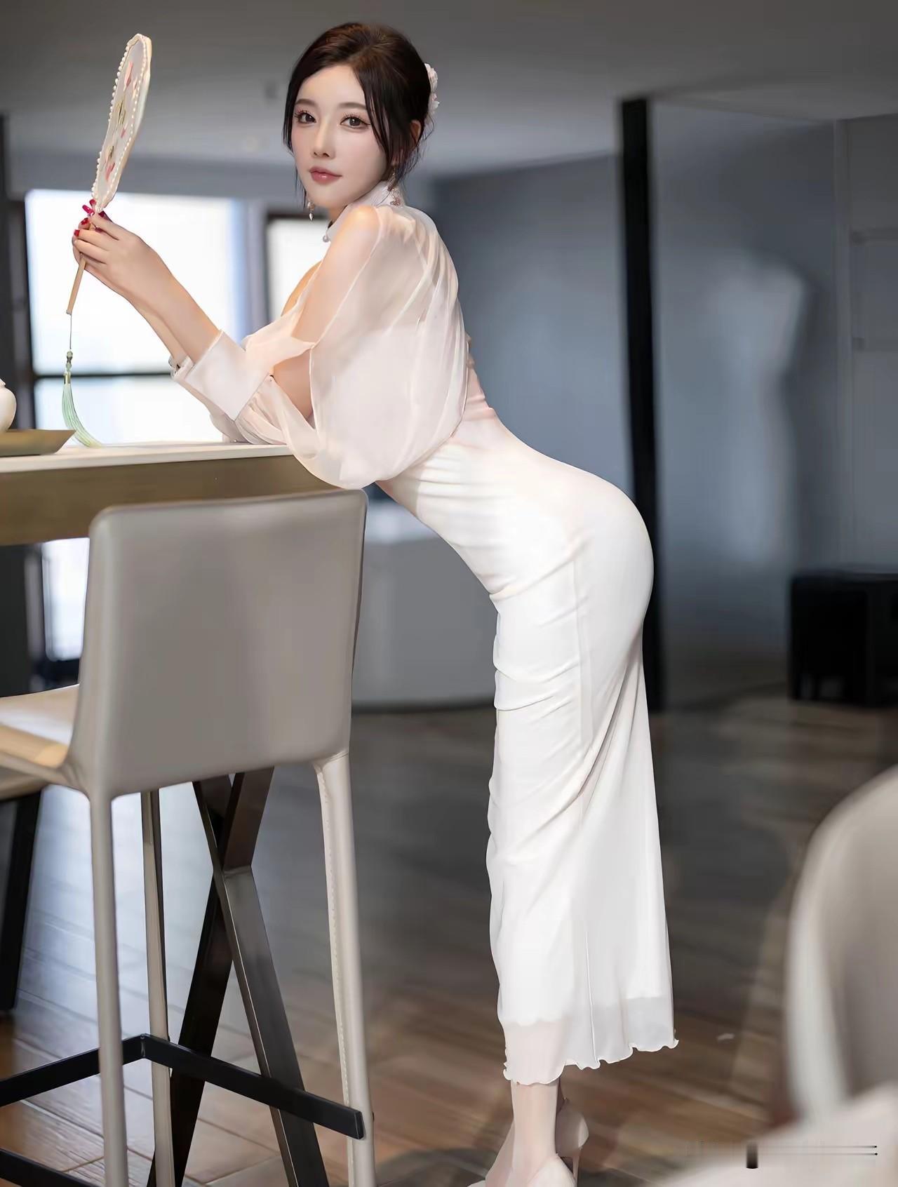 杨晨晨，身着白裙手持团扇，回眸瞬间惊艳时光，优雅曲线与古典韵味完美融合。