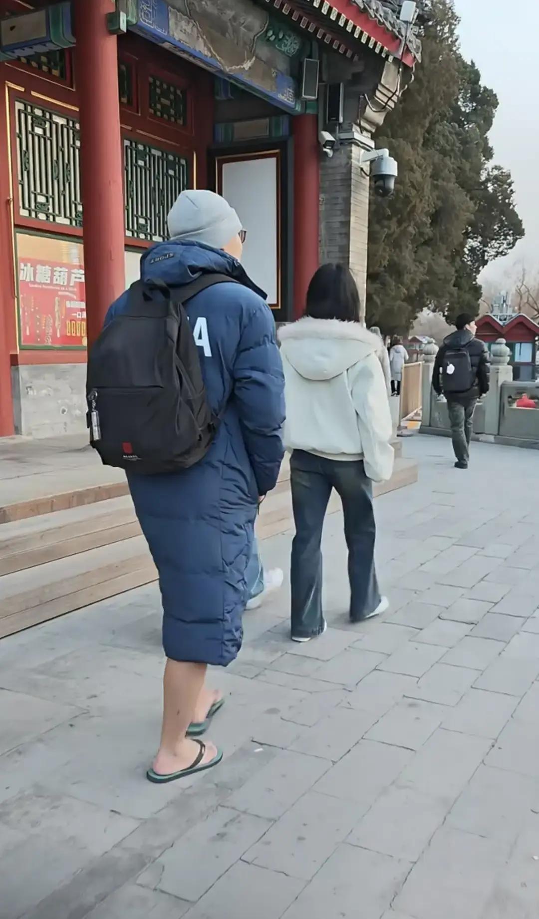 颐和园昆明湖结冰那天，一位大哥裹着长款羽绒服，脚踩蓝色人字拖在雪地里慢悠悠走。