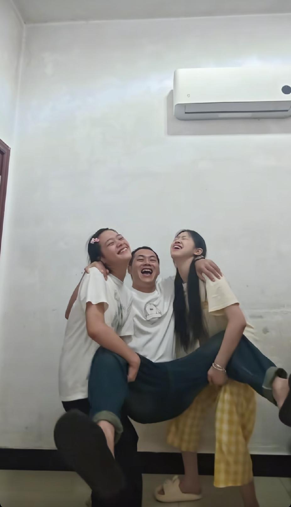 男子蹲下身子，想抱起身旁的两名女孩，女孩的一个举动，却让男子笑着笑着就落泪了。
