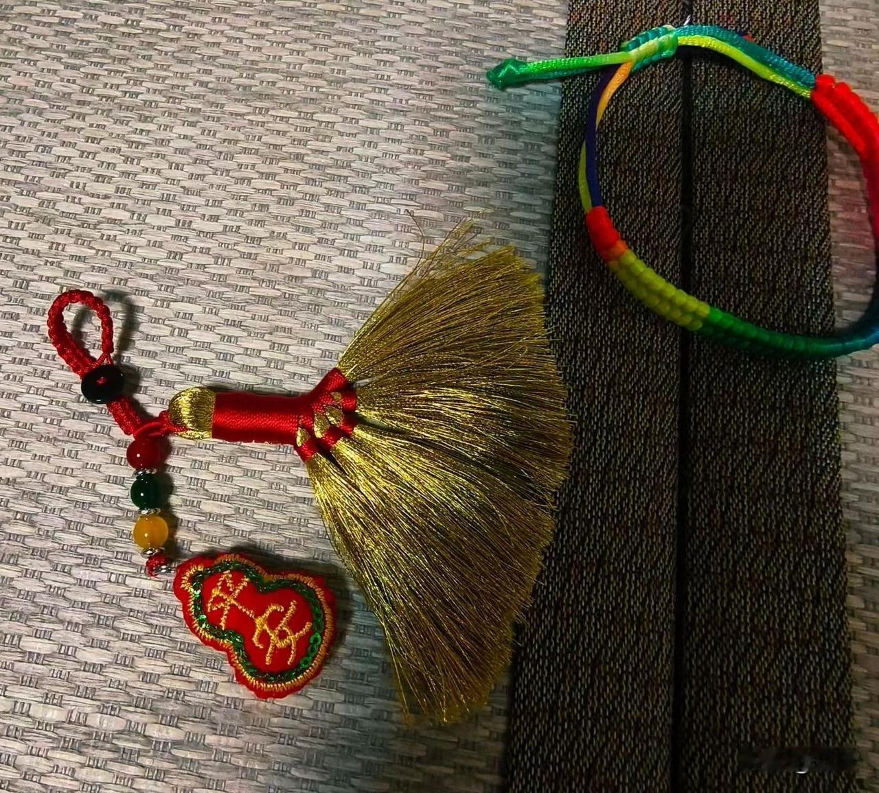 昨天回家一进屋，我妈就把两件小可爱送给我，一个是五彩手绳，一个是平安金扫帚挂件，
