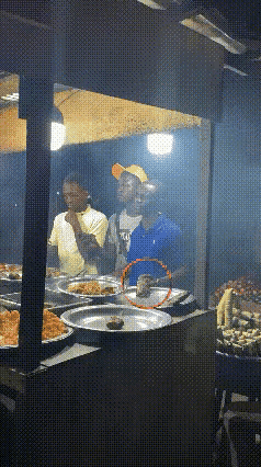 这应该是一家熟食店，不知道是在国内还是在国外，这个站在摊位前的这个穿蓝衣服的男子