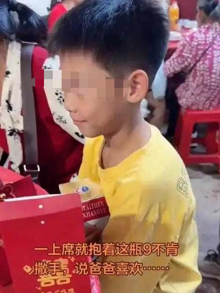 离谱！宝妈带娃吃席，桌上的一瓶酒被小男孩死死护住。谁来讨要都坚决不让，，一直说爸
