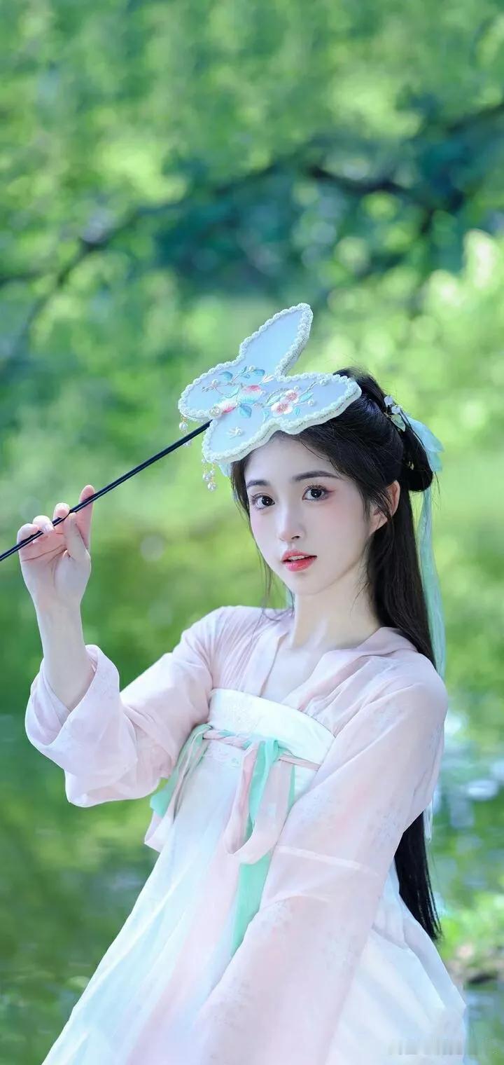 仙气飘飘的汉服少女，手持团扇，置身于绿意盎然的森林中。
