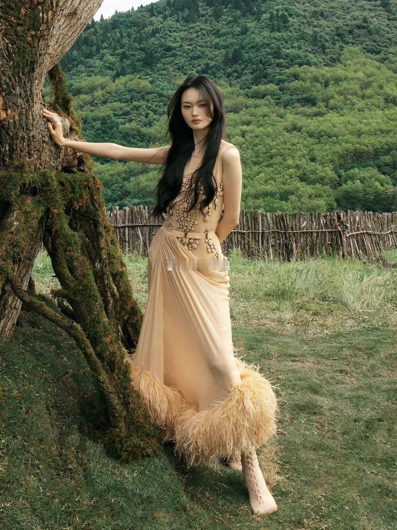 贺聪身着Mugler 2026春夏系列裸色薄纱长裙亮相，轻盈羽毛与薄纱交织，如九