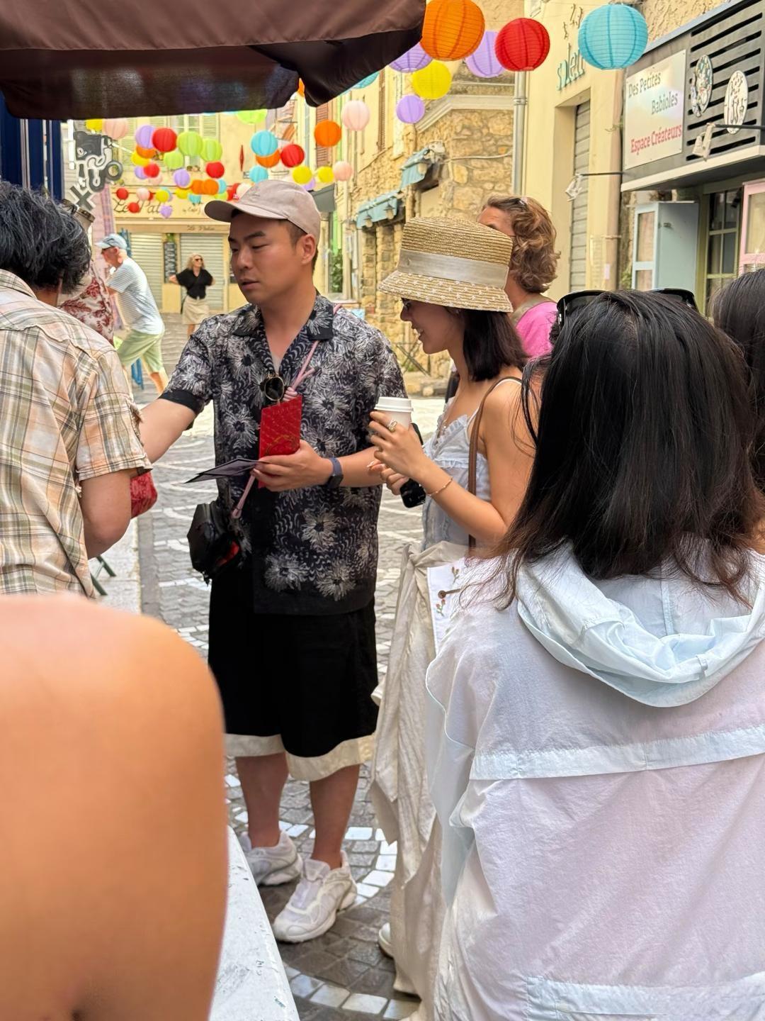 赵今麦和一男性友人现身法国南部旅游，她头戴法式麦秆帽，白色吊带长裙，背着单间背包