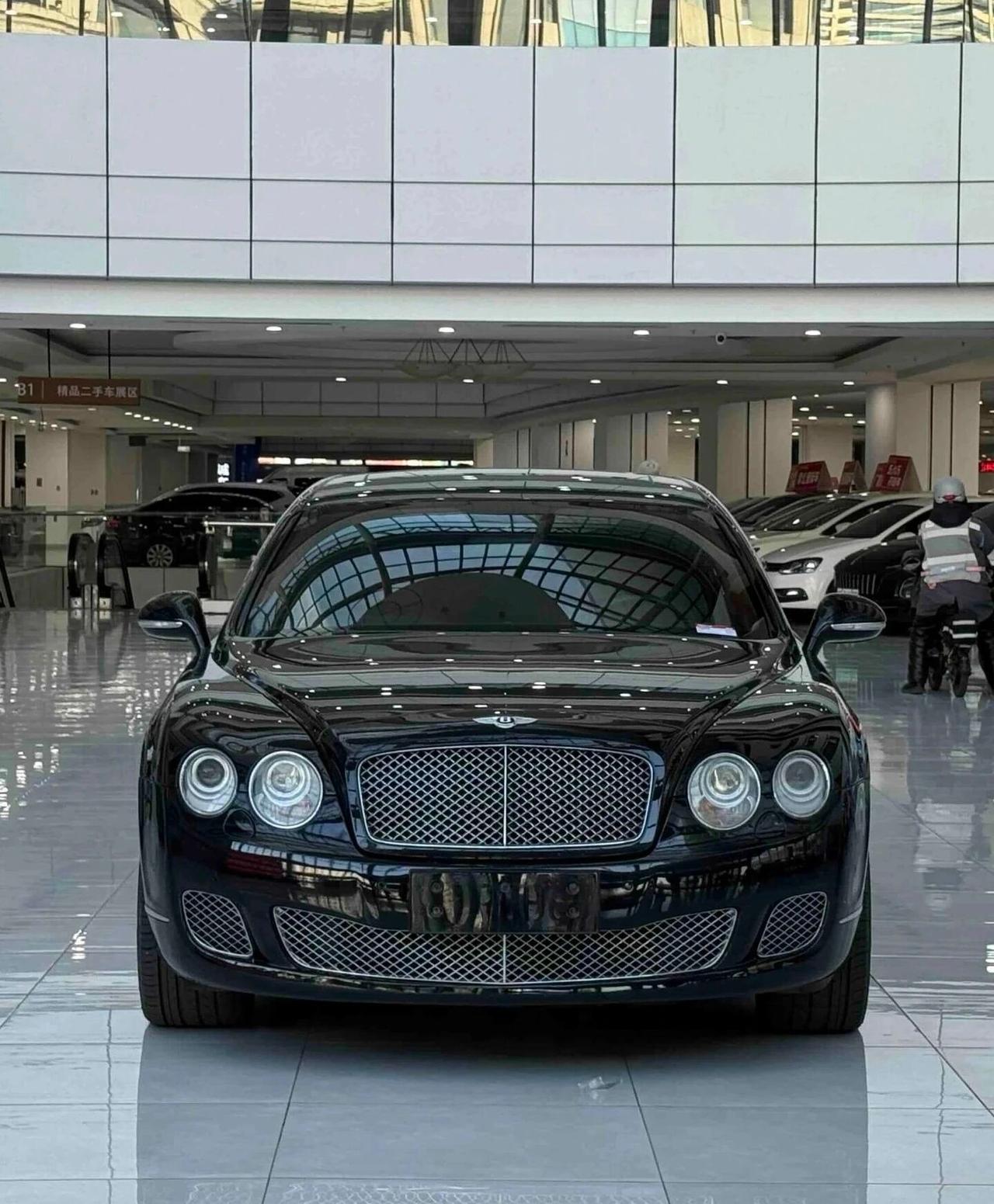 20万买台二手宾利，是圆梦捷径还是修车噩梦？在二手车展厅，一台黑色宾利飞驰旁立着