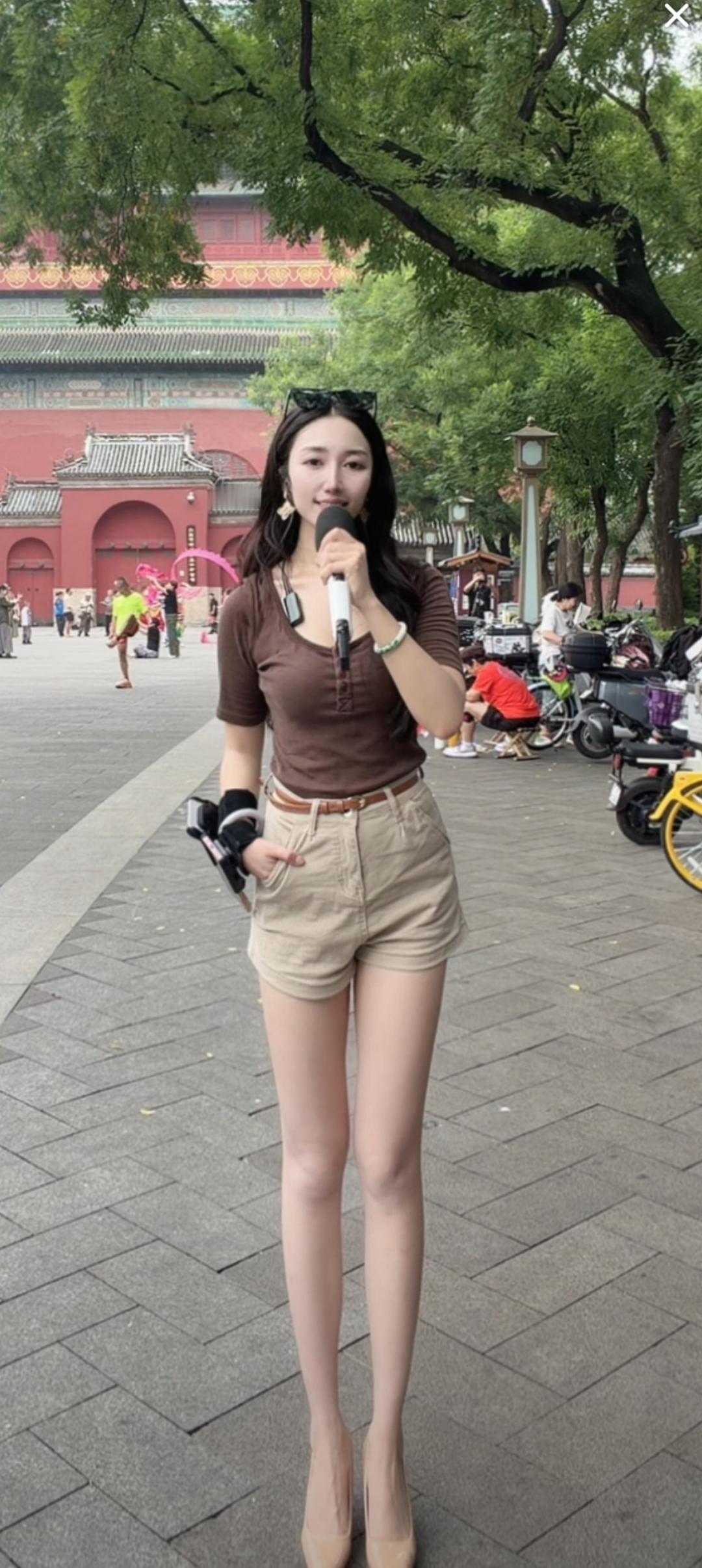 一位美女在街头拿着麦克风唱歌。