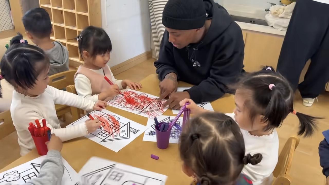 某地幼儿园专门请黑人外教来教小朋友画画艺术，只见这位黑人外教让孩子们围到桌子旁边