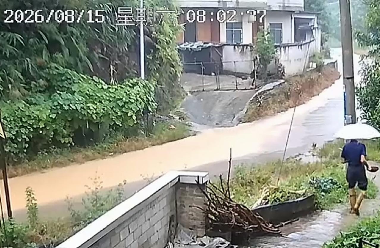 8月15日，广西平南突降暴雨，形成的积水猛烈的冲击着山体和路面。老人打着伞离开家