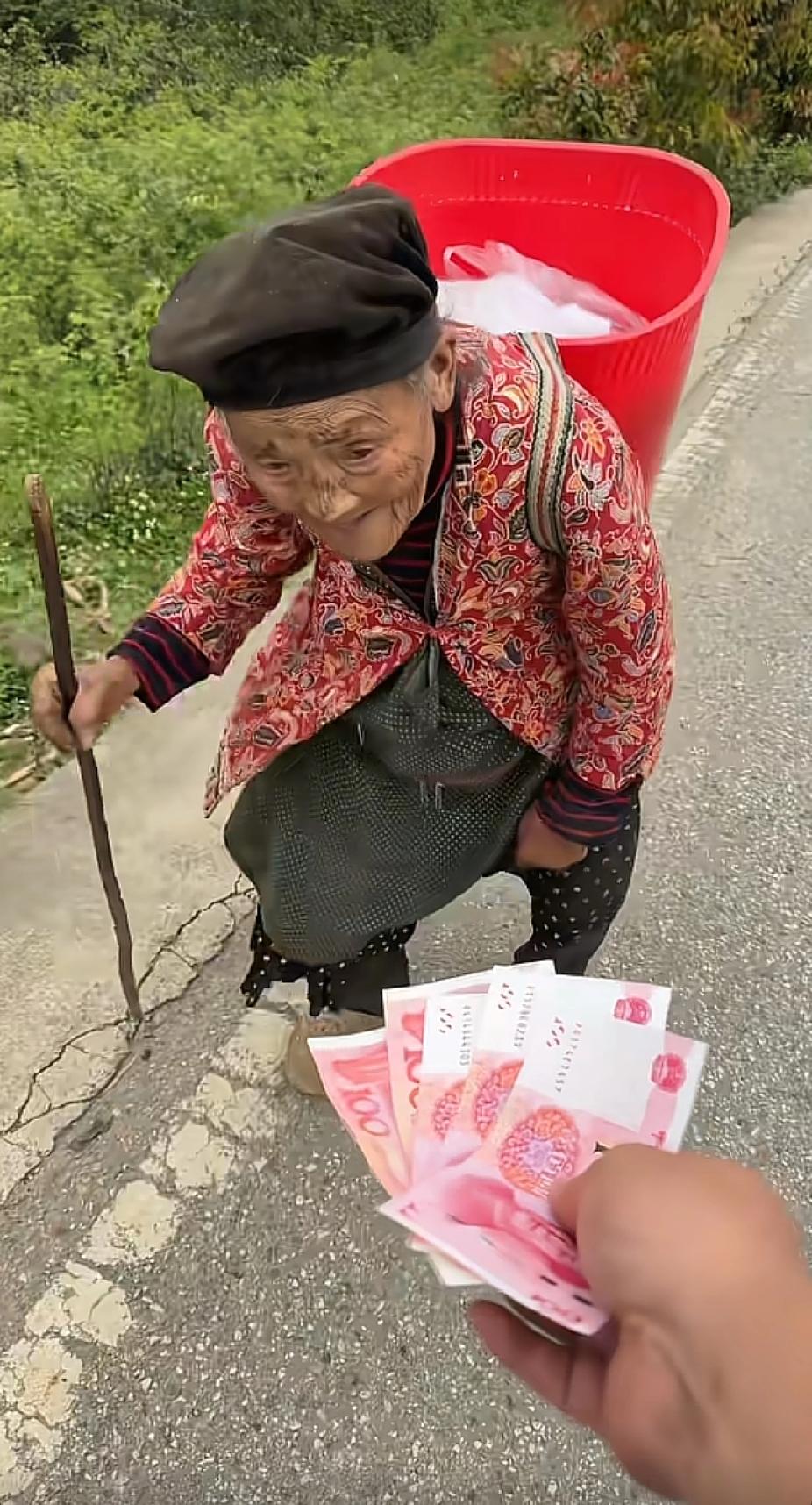 老人背着东西，佝偻着身子吃力费劲地走在路上，面前突然伸出的一只手，让人看着瞬间感