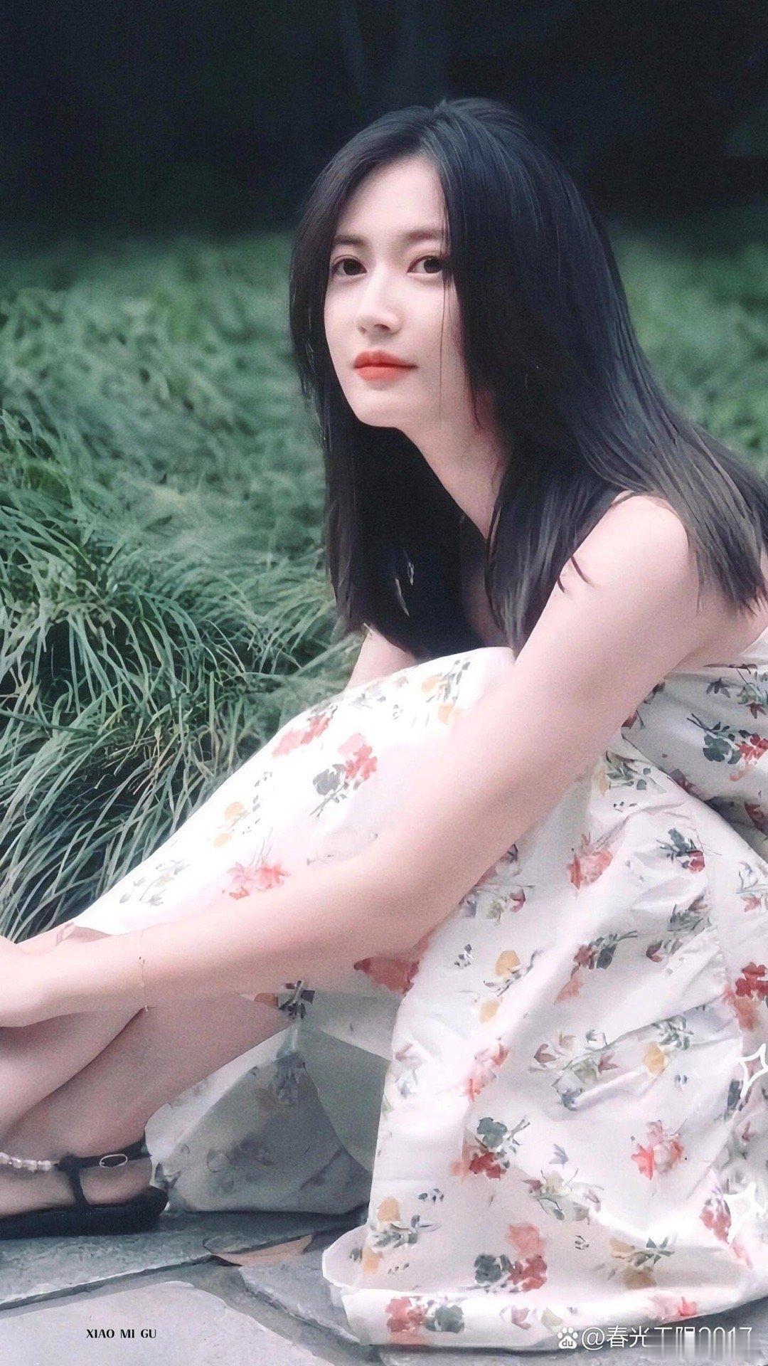 陈钰琪坐在石阶上，裙摆轻轻拂过青草，静静感受夏日的清新。 