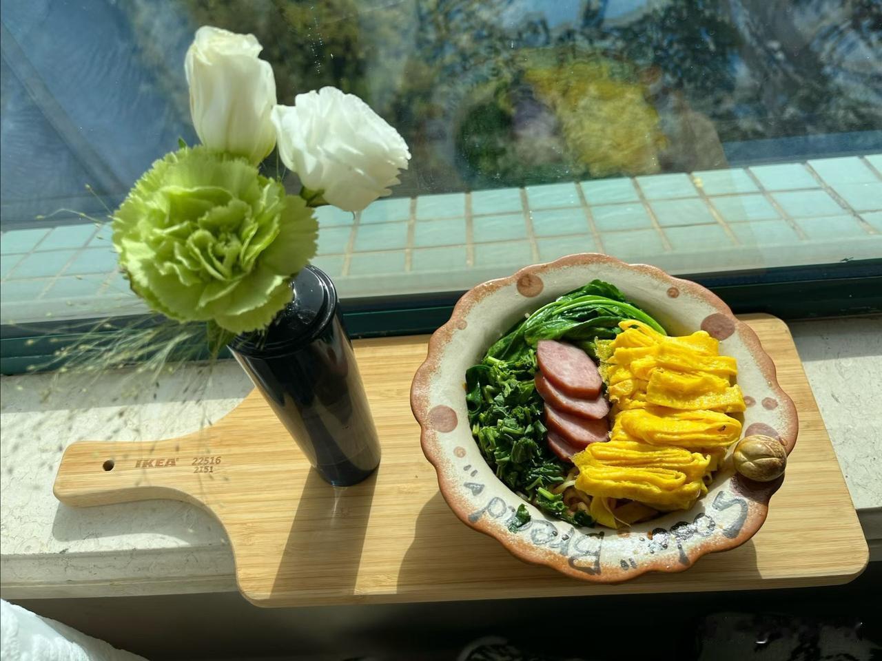 午后的阳光漫过窗沿，把瓷砖的浅青晕染成了柔和的光斑。厨房案头的绿色康乃馨与白郁金