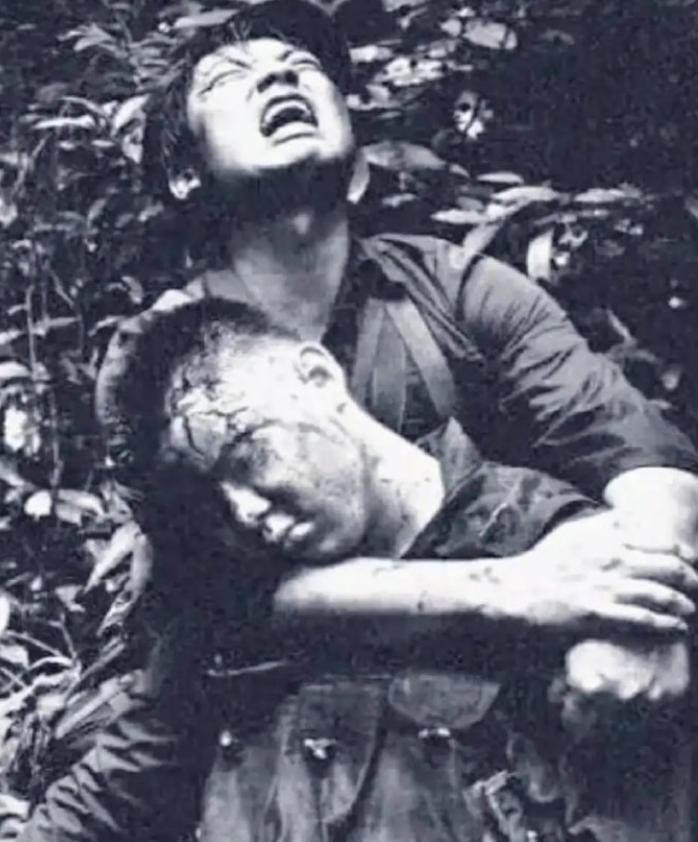 1987年的老山战役时期，照片中，战士李发忠泪眼婆娑地抱着他的战友陈为民的遗体，
