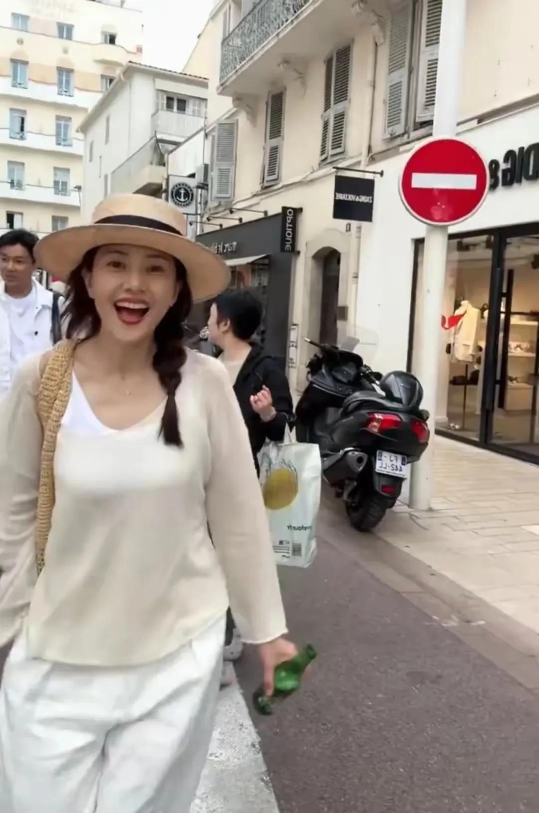 戛纳街头，高圆圆一身休闲白装逛超市，被啤酒吸引后竟直接拎瓶畅饮，漫步街头笑容肆意