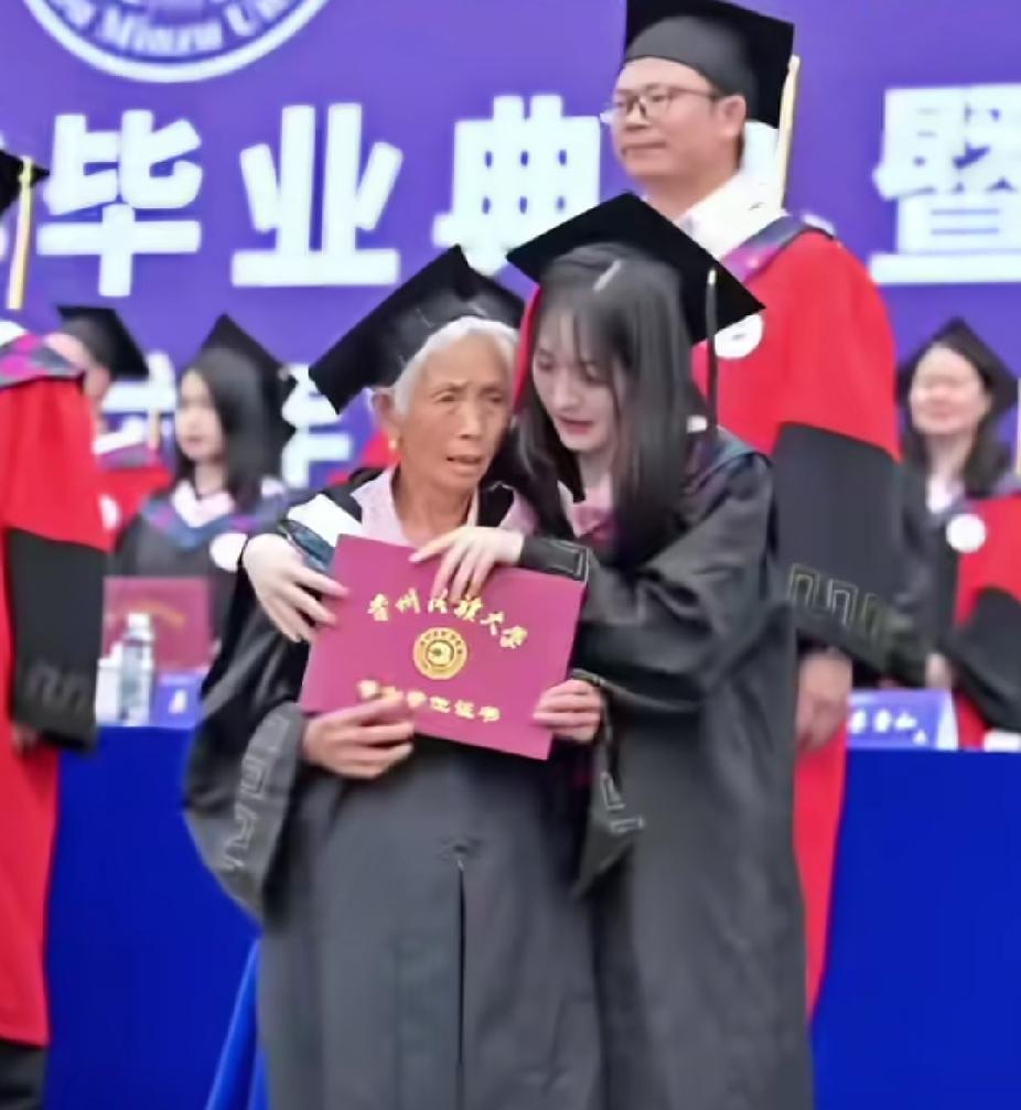 一场大学毕业典礼正在举行，一名大学生女孩，扶着一位白发老人走上台的瞬间，台下的人