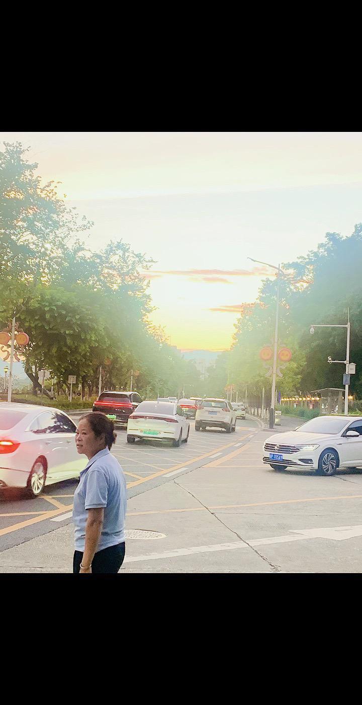 夕阳下的城市街道，车流不息，行人匆匆。