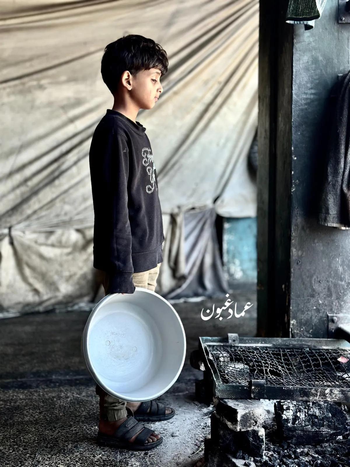 在以色列加沙北部的饥饿战争中，一名饥饿的巴勒斯坦男孩背着一个空锅，等待有人给他和
