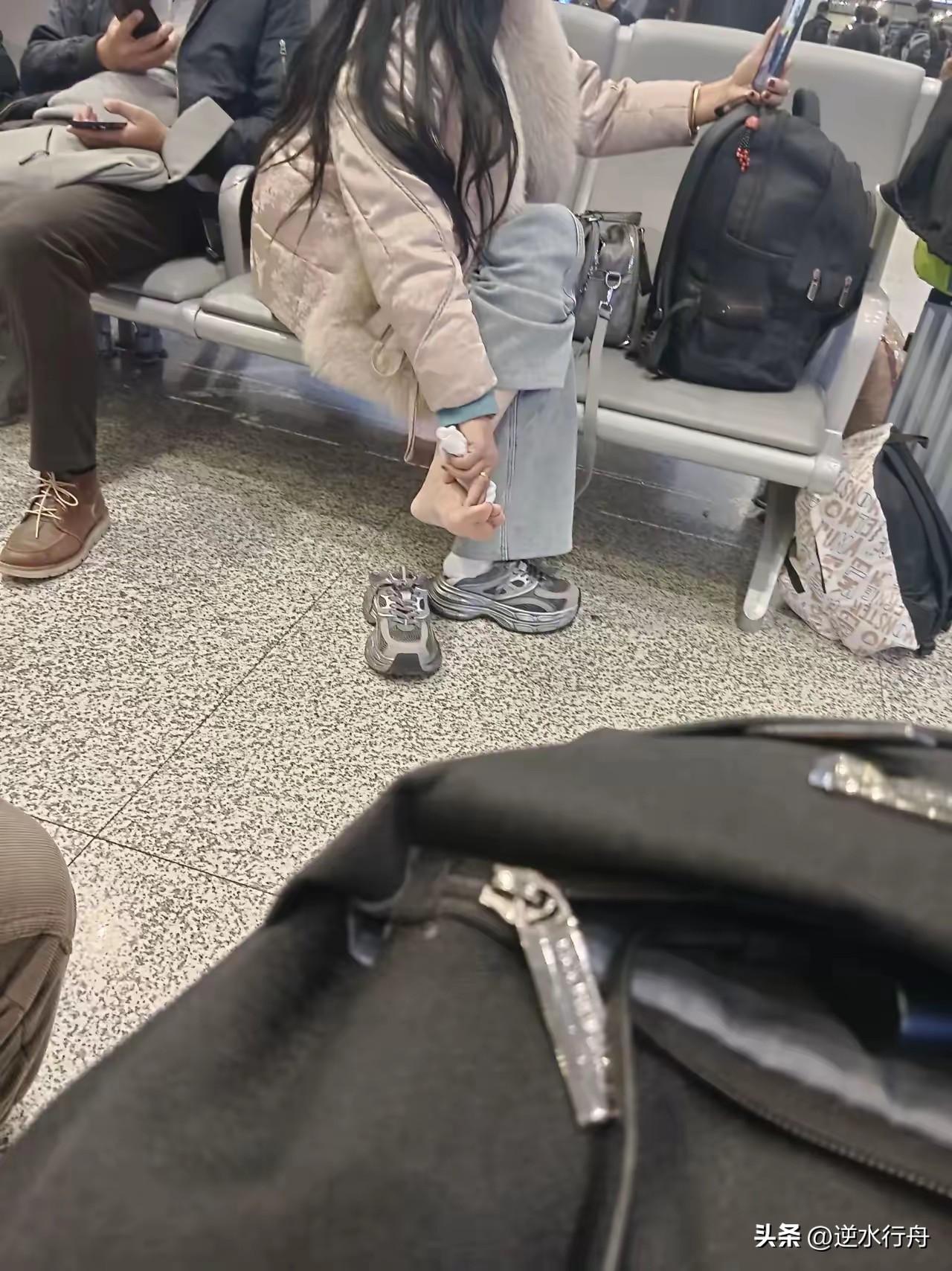 这个美女可能脚太痒了，在候车室脱了袜子挠痒。这是一个看起来斯文好看的年轻女子，完