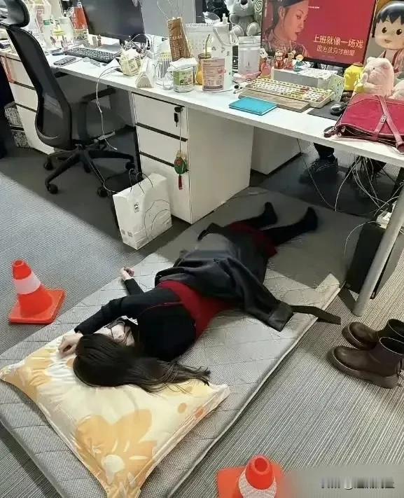办公桌下打地铺，职场人的午休能有多拼！
一个年轻女孩蜷在办公桌下的席子上睡着了，