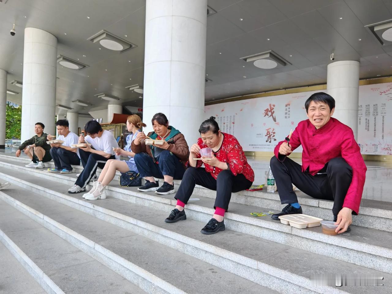在湖北剧院，午餐时间一到，演职人员席地而坐就餐。这场景看着有些心酸，却也满是为艺