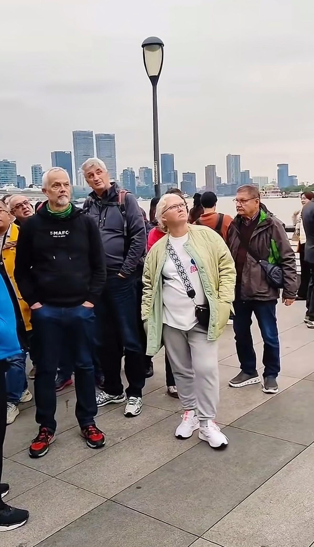 很好奇，一群美国人，在上海外滩，仰望着什么呢！一个个都很惊讶，表情看似很凝重！应