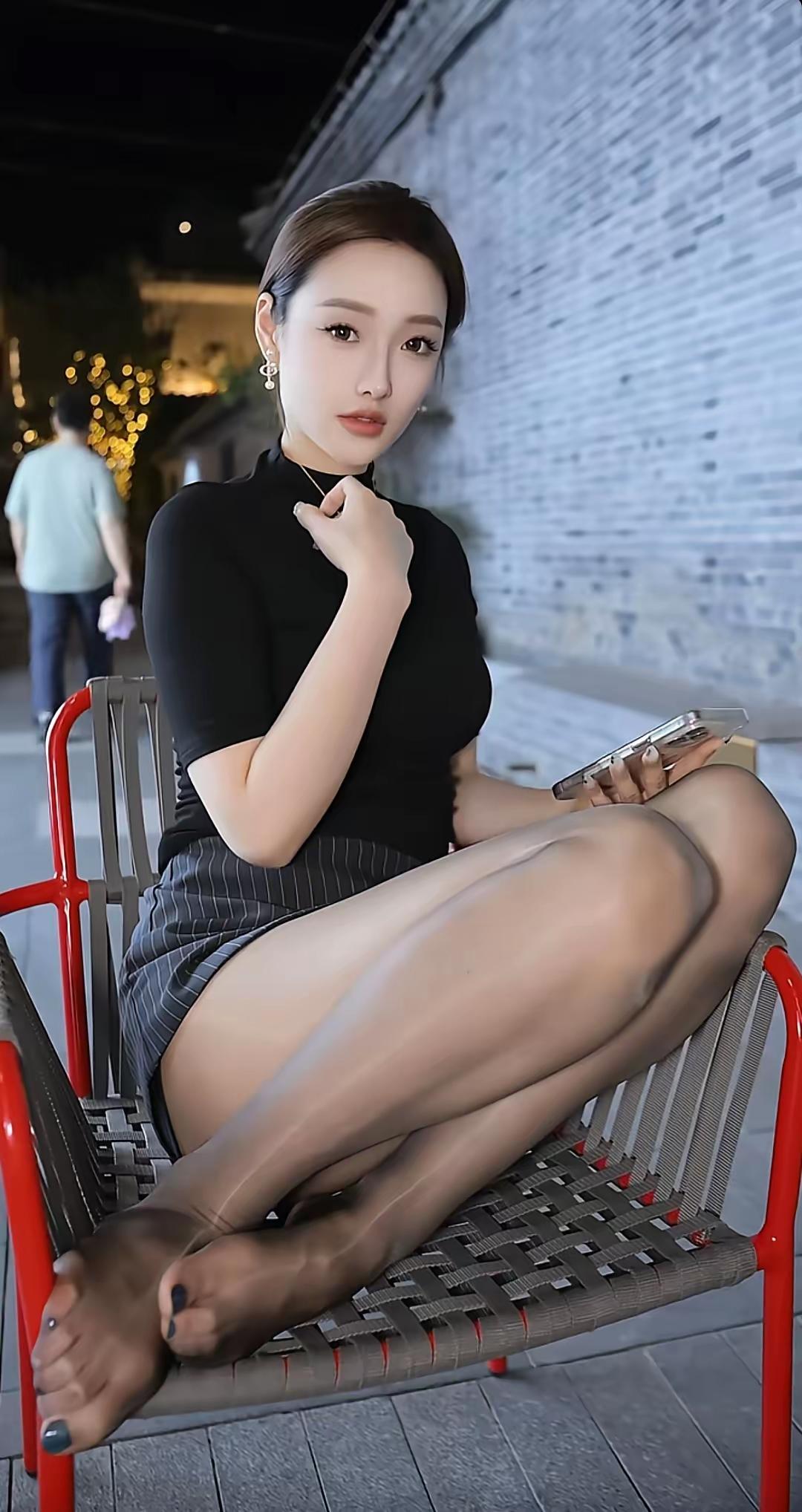 夜晚的街头，优雅的坐姿，时尚的黑衣与高跟鞋，尽显都市女性魅力。美女的美丽体现在何