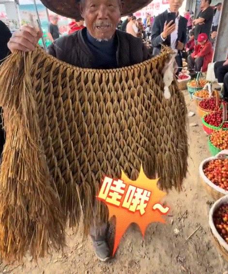 山东一集市上，一大爷本来是赶集卖樱桃的，结果大爷身上披着的一件纯手工蓑衣，却引来