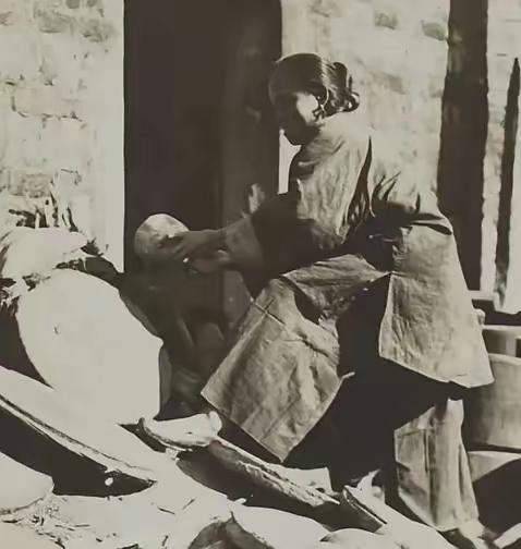 她是一名清朝刽子手的老婆，正在自家门口晒三个骷髅头。
 
她是一名清朝刽子手的老