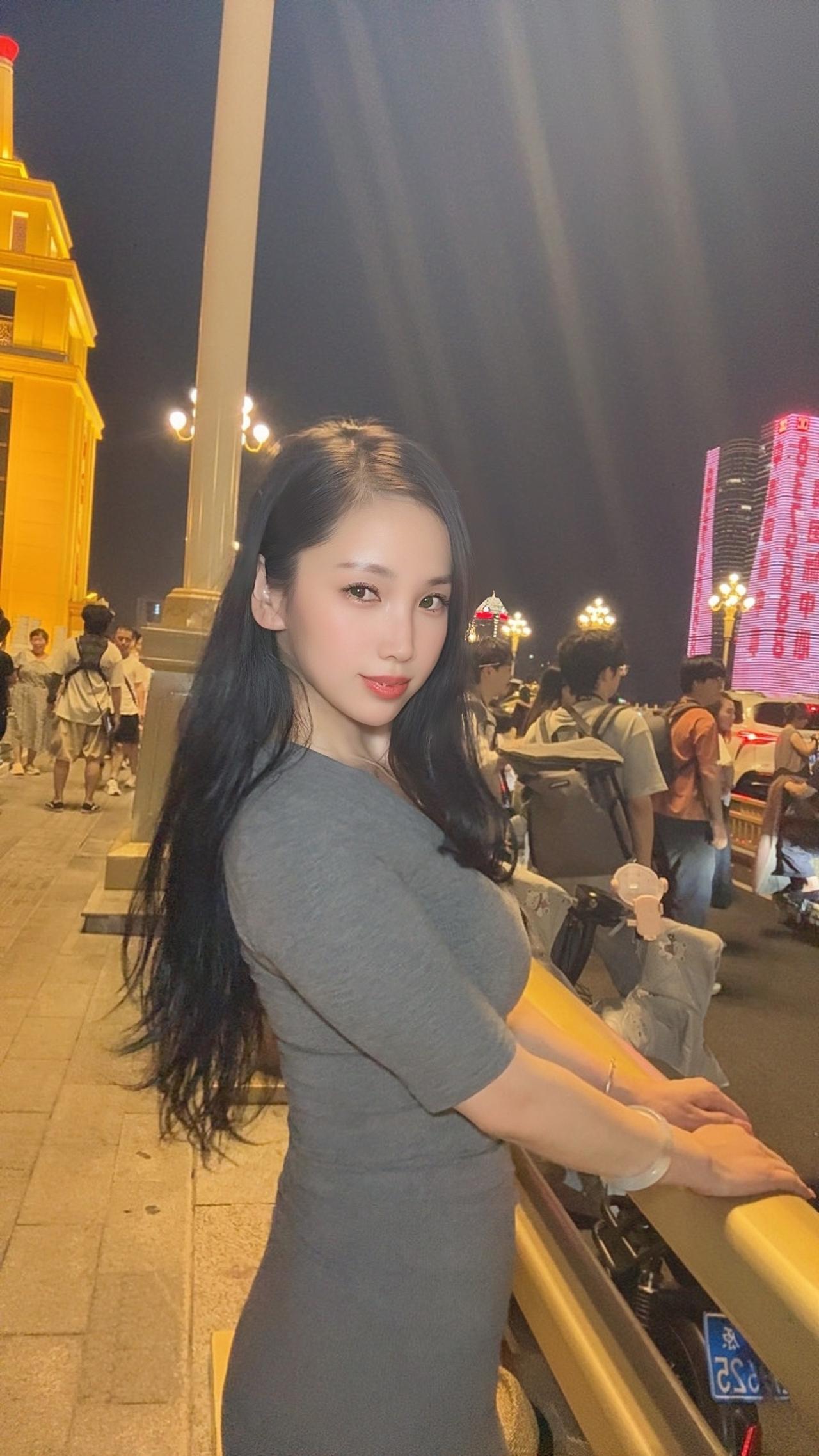 夜景下，长发美女靠车摆拍。