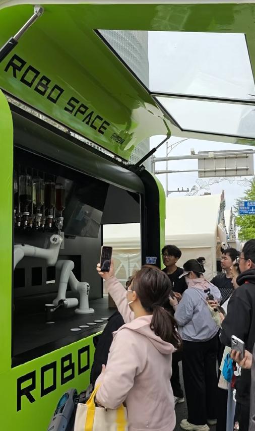 【金融街嘉年华机械臂特调饮品引围观，大量消费者举手机打卡记录】4月26日，202