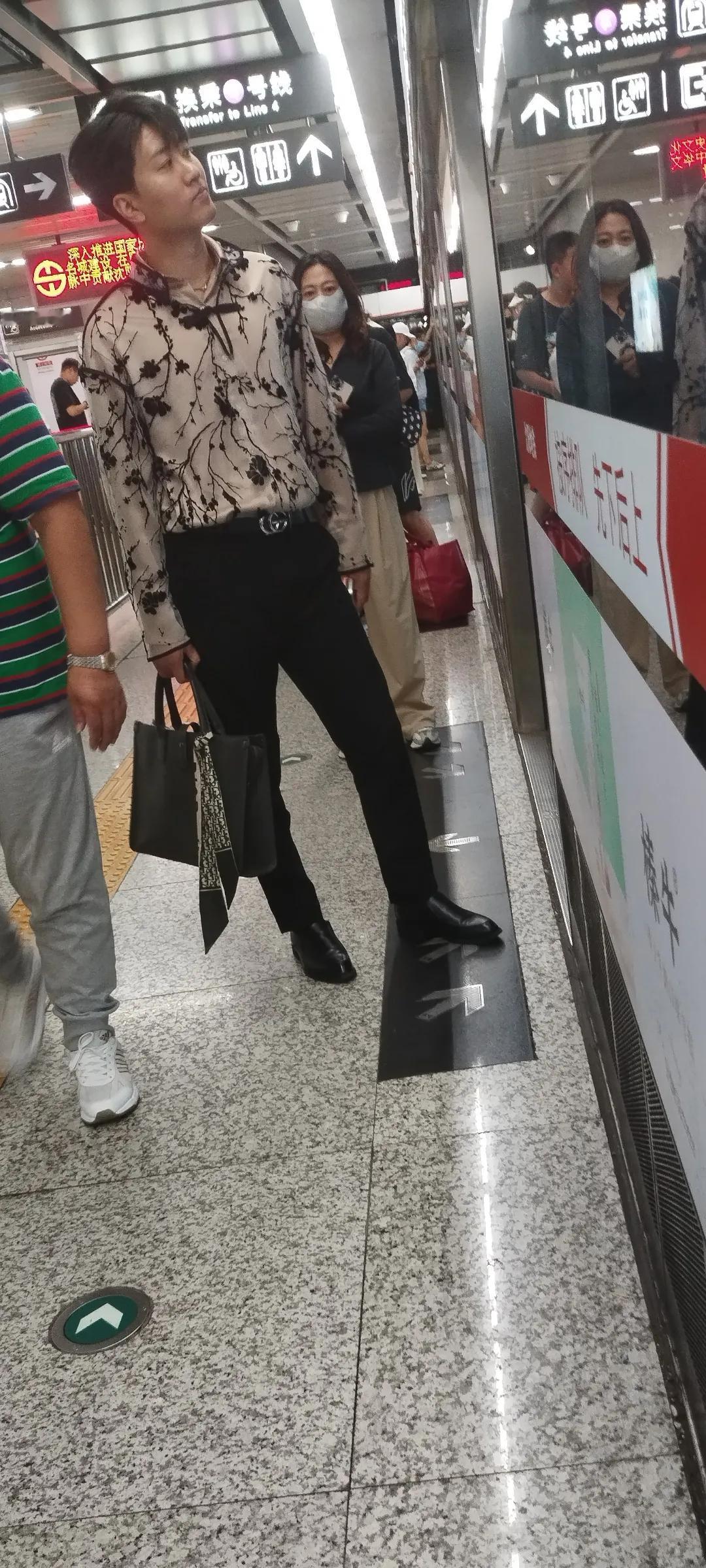 地铁站台上小伙等车，这个姿势太酷了。

小伙这一身行头也不一般。

领带挂在了皮